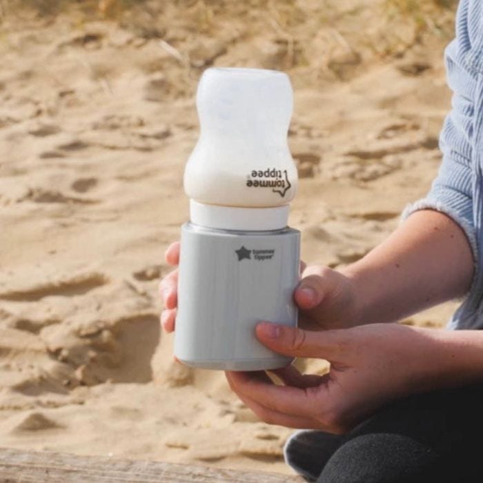 A bottle being warmed at the beach using a LetsGo Portable Baby Bottle Warmer