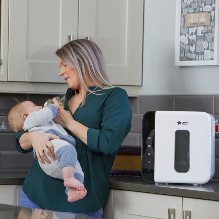 mum feeding baby with UV steriliser in foreground