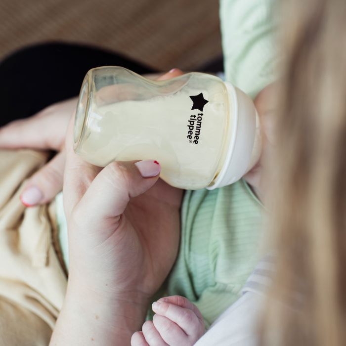 Parent feeding baby milk from a PPSU bottle