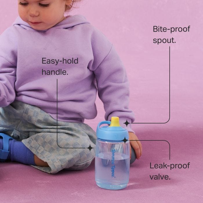 Toddler sitting on the floor with an Active Spout cup against a pink background with pointers to the key product features