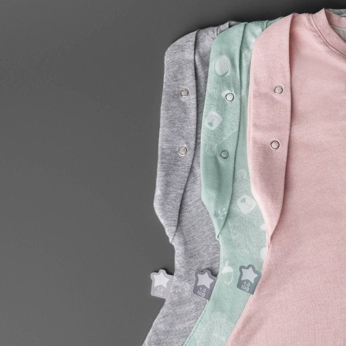 Three folded sleeping bags on a grey background