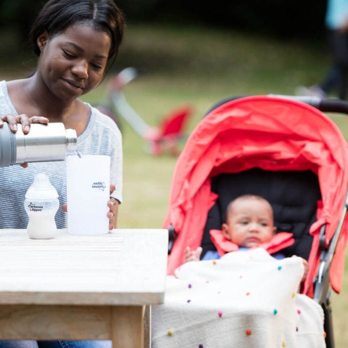 Mum preparing a Tommee Tippee bottle using Travel Bottle and Food Warmer out and about 