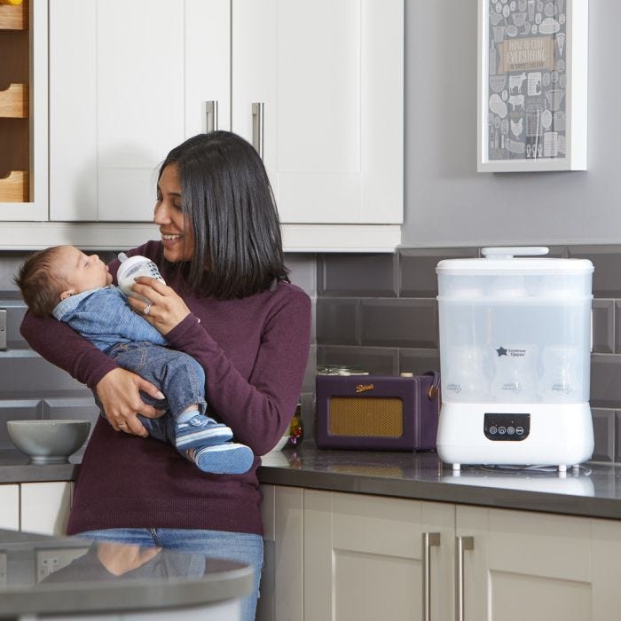Mom feeding baby with Advanced Electric Steri-dryer in the background