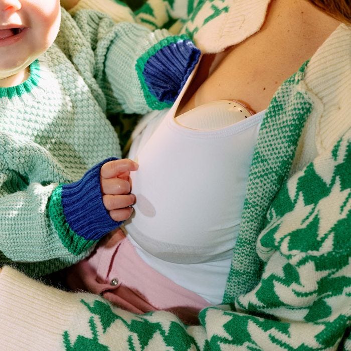 Woman using the double wearable breast pump while her baby sits on her lap