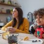 toddler-smiling-holding-pink-Easiflow-360°-Cup-with-handles-and-bear-design-next-mum-at-breakfast