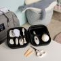 Kit de soin comprenant des accessoires pour les cheveux et les ongles dans une mallette de voyage noire à côté d&apos;un paquet.