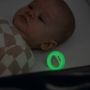 Baby sleeping with glowing in the dark pacifier next to them