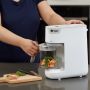 Woman placing veggie-filled basket into the food maker to steam and blend