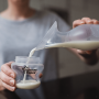 mum pouring milk form the silicone breast pump into closer to nature bottle