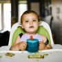 child at the table holding Essential Free Flow First Cup