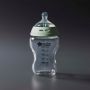 Glass baby bottle against a grey background