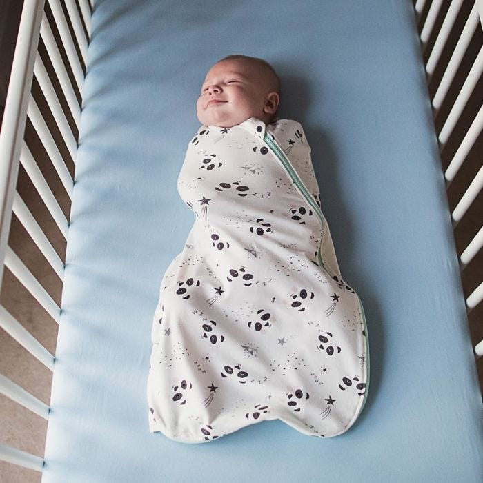 Baby lying in cot wrapped in The Original Grobag Little Pip Easy Swaddle
