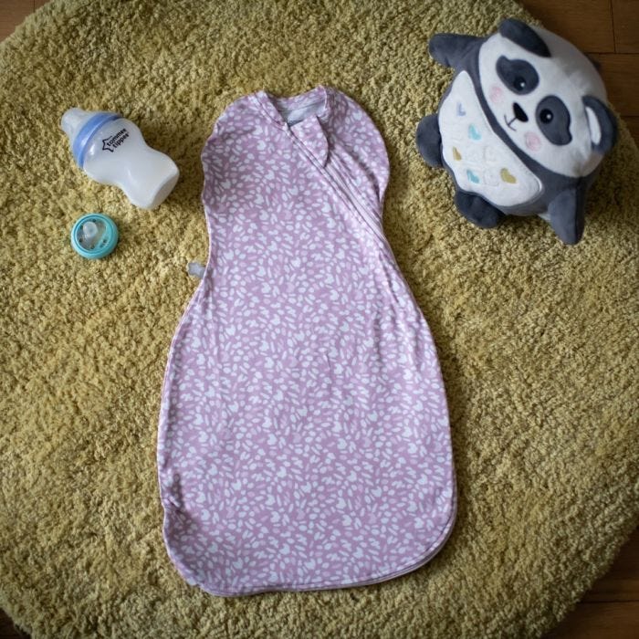 Tommee Tippee Earth Grape Easy Swaddle on ground with baby bottle and pip the panda