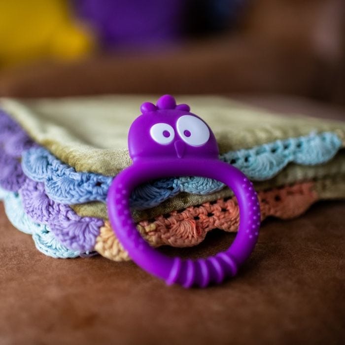 Tommee Tippee Kalani sensory teether mini in purple lying on a cushion 