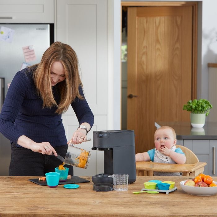 Woman making puree for her baby who sits in a highchair next to her