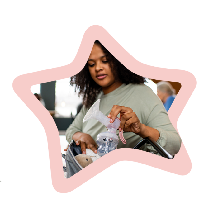 Woman at a cafe placing manual breast pump into her grey changing bag surrounded by a pink star.