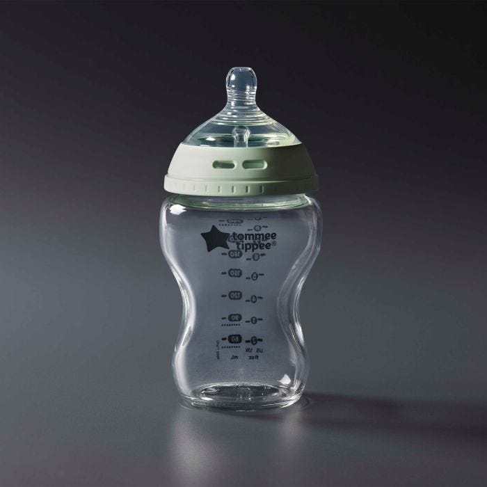Glass baby bottle against a grey background