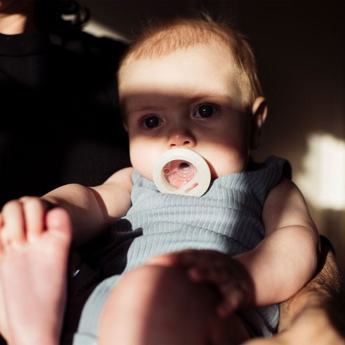 Baby with soother in mouth with shadow over face