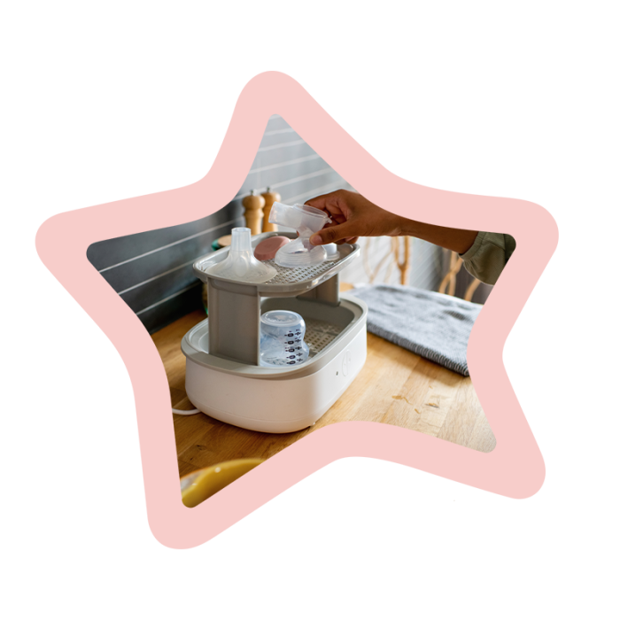 Woman placing separated parts of the electric pump in an electric steam steriliser surrounded by a pink star