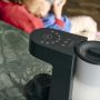 Image of Perfect prep machine on a kitchen counter with a woman feeding a baby in the background