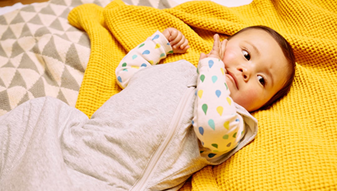 Bébé allongé sur le lit portant un sac de couchage