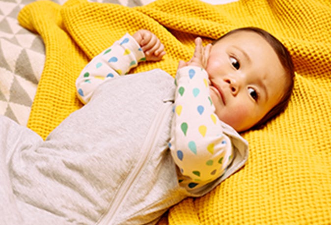 Bébé allongé sur le lit portant un sac de couchage