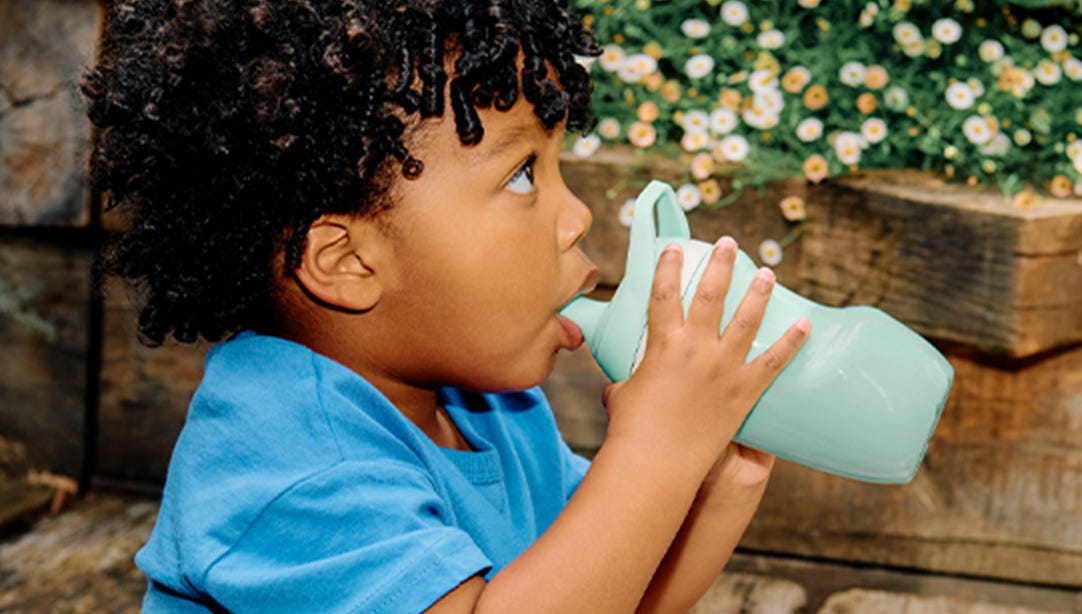 Baby outside sipping from insulated bottle 