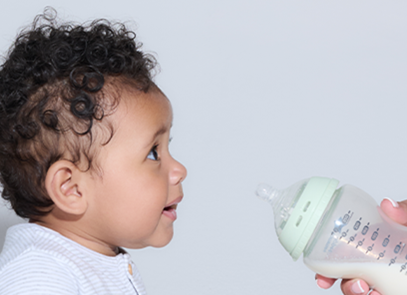 a mum offering her baby a bottle of milk 