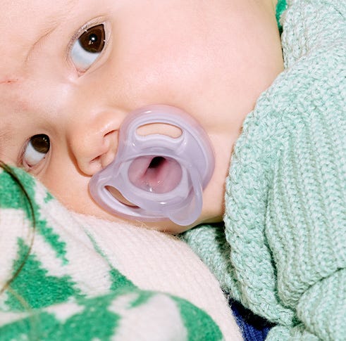 un bébé avec une sucette ultra-légère tommee tippee violette dans la bouche 